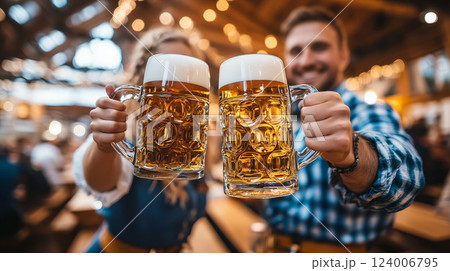 Happy couple wearing traditional Bavarian clothes holding two large beer mugs at Oktoberfest in Munich, Germany 124006795