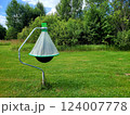 Horsefly trap against green trees. Photo of black ball insect trap on stand in mown meadow. Agricultural equipment for insect protection. 124007778