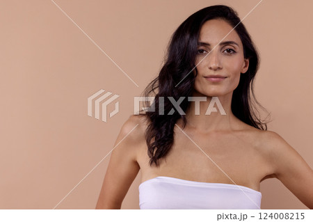Studio portrait of a charming brunette woman in a white top with beautiful wavy hair and perfect skin. Studio portrait of a charming brunette woman in a white top with beautiful wavy hair and perfect skin. 124008215