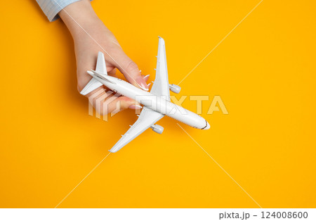 Woman playing with miniature passenger plane. Concept of flights, travel and tourism. Excitement of upcoming trips. Tourism trends, vacation ideas 124008600