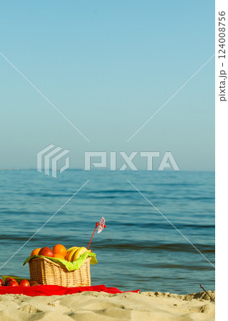 Picnic basket on blanket near sea Picnic basket on blanket near sea 124008756