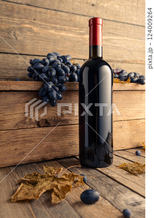 Bottle of red wine with blue grapes on a wooden table. Bottle of red wine with blue grapes on a wooden table. 124009264