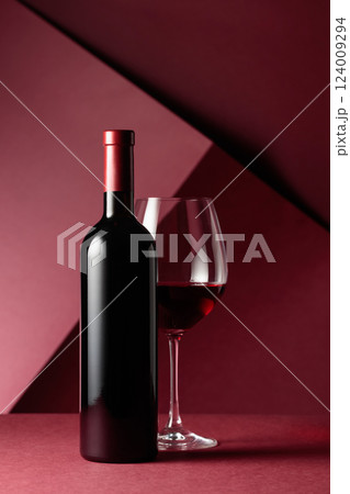 Bottle and glass of red wine on a red background. Bottle and glass of red wine on a red background. 124009294