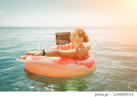 Woman laptop sea. Freelancer woman in sunglases floating on an inflatable big pink donut with a laptop in the sea. People summer vacation rest lifestyle concept Woman laptop sea. Freelancer woman in sunglases floating on an inflatable big pink donut with a laptop in the sea. People summer vacation rest lifestyle concept 124009515