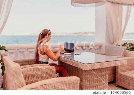 Woman coffee cafe laptop sea. Modern businessman in white uniform working on laptop in coffee shop. Woman sitting at a coffee shop with mobile phone drinking coffee. 124009560