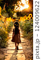 Young girl walks along a sunlit path lined with sunflowers during golden hour in a serene garden 124009622