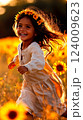 Joyful girl wearing sunflower crown smiles brightly amidst a vibrant field of sunflowers on a sunny day 124009623