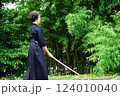剣道着姿のシニア女性が、屋外で竹刀を持ち、一人稽古をしている 124010040