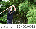 剣道着姿のシニア女性が、屋外で竹刀を持ち、一人稽古をしている 124010042