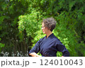 剣道着姿のシニア女性が、屋外で竹刀を持ち、一人稽古をしている 124010043