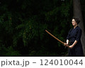 剣道着姿のシニア女性が、屋外で竹刀を持ち、一人稽古をしている 124010044