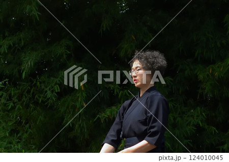 剣道着姿のシニア女性が、屋外で竹刀を持ち、一人稽古をしている 剣道着姿のシニア女性が、屋外で竹刀を持ち、一人稽古をしている 124010045