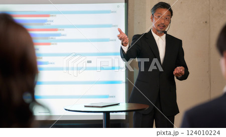 スライドの前でプレゼンをするシニア男性 124010224