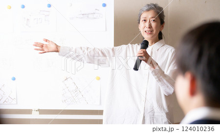 ホワイトボードの前でスピーチをするシニア女性 124010236