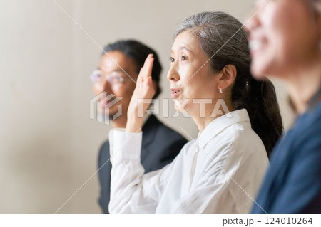 手を挙げて発言をするシニア女性 124010264