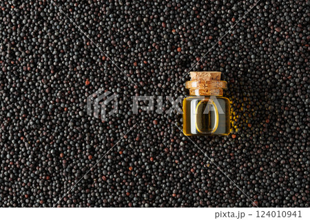 Small glass bottle containing golden oil resting on bed of rape seeds Small glass bottle containing golden oil resting on bed of rape seeds 124010941