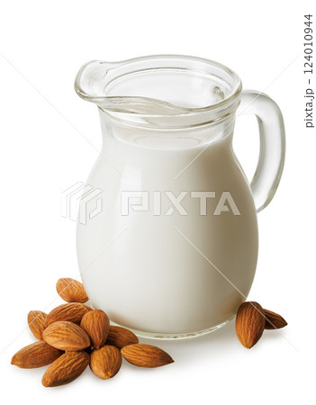 almond milk in glass jug and pile of nuts isolated on white background 124010944