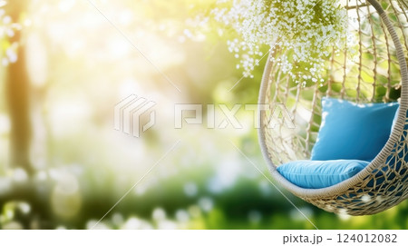 Springtime hanging chair with blue pillows surrounded by blooming flowers in a lush garden 124012082