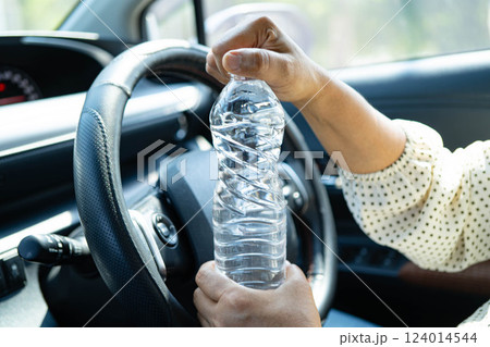 Asian woman driver hold cold water for drink in car, dangerous and risk an accident. Asian woman driver hold cold water for drink in car, dangerous and risk an accident. 124014544
