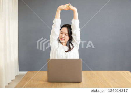 PC前で伸びをするアジア人女性01 124014817