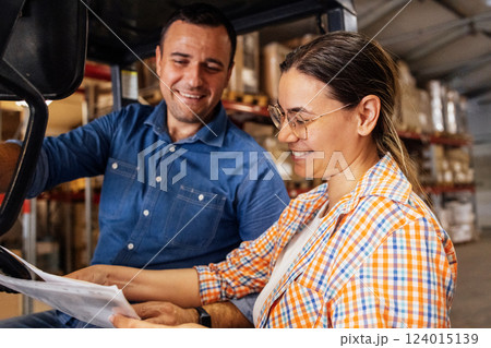 Young employees work in the warehouse. A smiling man and a woman in casual clothes mark the availability of goods on the shelves. Young employees work in the warehouse. A smiling man and a woman in casual clothes mark the availability of goods on the shelves. 124015139