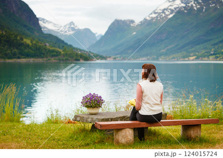 Woman tourist relaxing on fjord sea shore, Norway 124015724