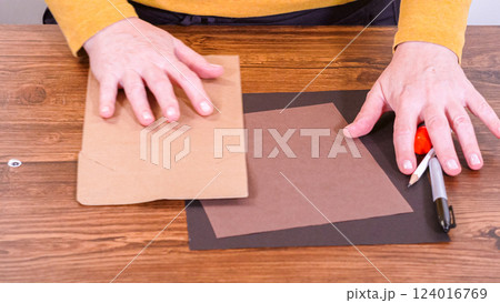 Step by step. Teacher guides online class through making a paper puppet from a brown bag, creatively using a wooden surface as a workspace. 124016769