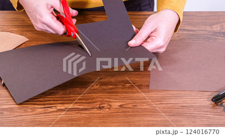 Step by step. Teacher guides online class through making a paper puppet from a brown bag, creatively using a wooden surface as a workspace. 124016770