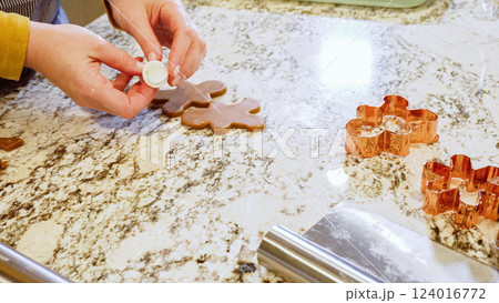 Using various festive cookie cutters, we're cutting out charming gingerbread cookies from the rolled dough on the sleek marble counter, bringing holiday cheer to the modern kitchen. 124016772