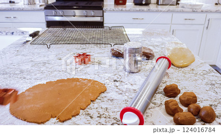 Using an adjustable rolling pin to roll out gingerbread cookie dough on the elegant marble counter in a modern kitchen, getting ready for festive holiday baking. 124016784