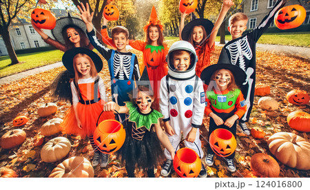A lively group of kids posing outdoors in a grassy area, wearing colorful Halloween costumes. The costumes range from pumpkins and skeletons to superheroes and astronauts, with the children showcasing 124016800