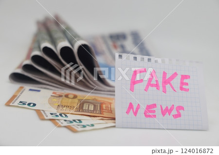 Roll up newspaper with a piece of paper that says fake news, corrupt journalism. Roll up newspaper with a piece of paper that says fake news, corrupt journalism. 124016872