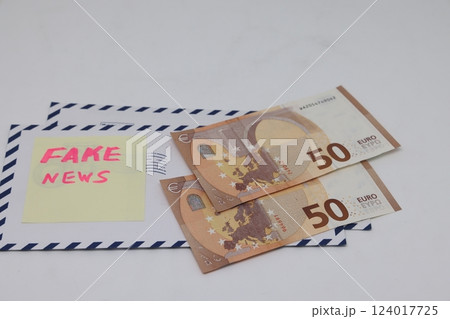 Banknotes in a yellow envelope on a light background. Fake news sticker on the envelope. 124017725