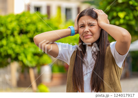 Displeased exhausted young Caucasian woman rubbing temples to cure headache standing on city street Displeased exhausted young Caucasian woman rubbing temples to cure headache standing on city street 124017917
