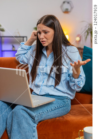 Angry stressed young Caucasian woman talking laptop using computer webcam video call on sofa at home 124017919