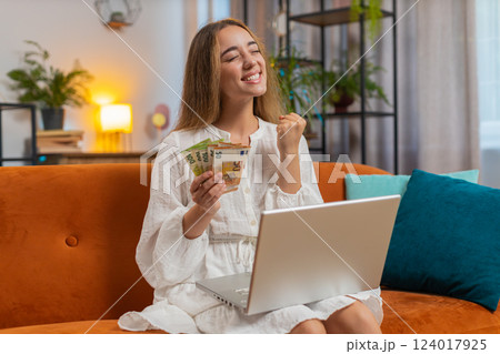 Rich happy young woman counting money euro cash using smartphone calculator sitting at home Rich happy young woman counting money euro cash using smartphone calculator sitting at home 124017925