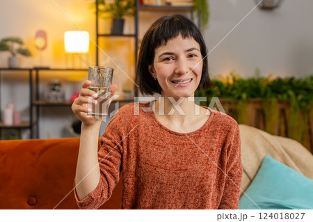 Smiling Caucasian woman sitting at home leading healthy lifestyle, drinking a glass of pure water 124018027