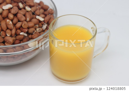 Peanuts in a bowl and a glass of orange juice. Separate on a white background. 124018805