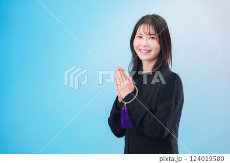喪服を着て手を合わせる女性(水色背景) 喪服を着て手を合わせる女性(水色背景) 124019580