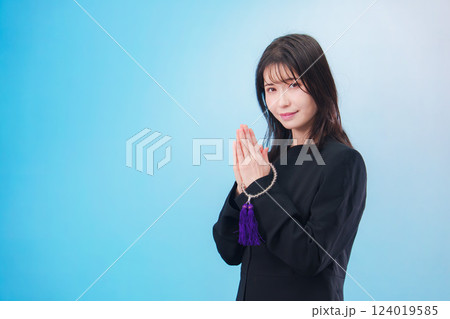 喪服を着て手を合わせる女性(水色背景) 喪服を着て手を合わせる女性(水色背景) 124019585