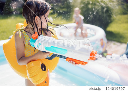 Joyful little girl in swimsuit with inflatable circle on terrace. Cute kids are messing around and splashing water 124019797