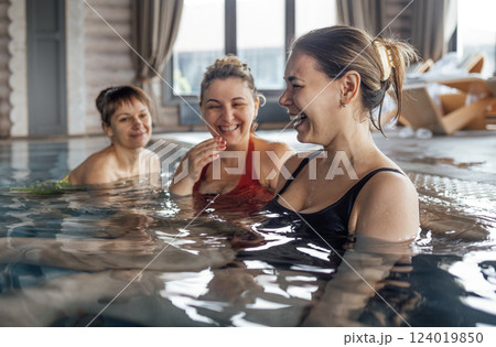 Three young attractive women are laughing and having a great time in the pool Three young attractive women are laughing and having a great time in the pool 124019850