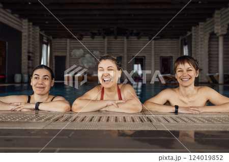 Three young attractive women are laughing and having a great time in the pool. Female friends swim and enjoy the weekend together. Three young attractive women are laughing and having a great time in the pool. Female friends swim and enjoy the weekend together. 124019852