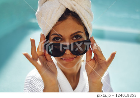 Relaxed caucasian female in sunglasses and a towel on her head sits at the poolside. Vacation and spa concept. Relaxed caucasian female in sunglasses and a towel on her head sits at the poolside. Vacation and spa concept. 124019855