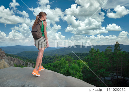 Young woman hiking alone on mountain footpath. Female hiker enjoying view of summer nature on wilderness trail. Active way of life concept 124020082