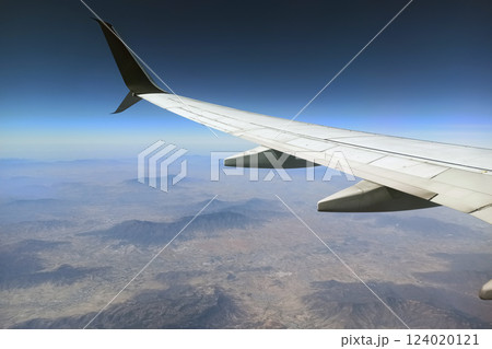 View through airplane window of commercial jet plane wing flying high in the sky. Air travelling concept View through airplane window of commercial jet plane wing flying high in the sky. Air travelling concept 124020121