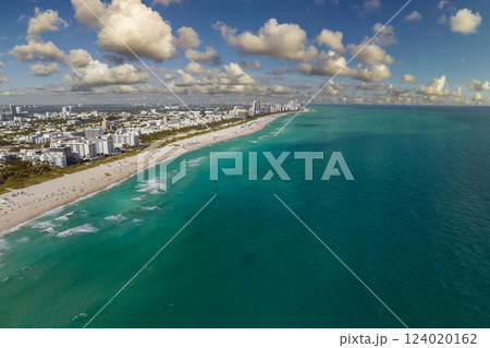 Travel destination and tourism infrastructure in southern USA. South Beach sandy surface with tourists relaxing on hot Florida sun. Miami Beach city with high luxury hotels and condos 124020162