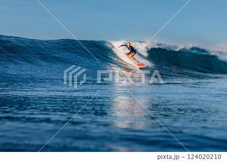 Woman surfer riding on a perfect wave on a sunny day. Surfing in ocean. Woman surfer riding on a perfect wave on a sunny day. Surfing in ocean. 124020210
