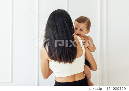 A young woman holds her beautiful baby. Charming mom with a sweet cute toddler 124020320