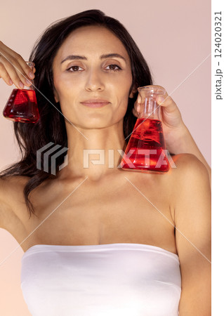 portrait of gorgeous young woman with glass flasks with red liquid portrait of gorgeous young woman with glass flasks with red liquid 124020321